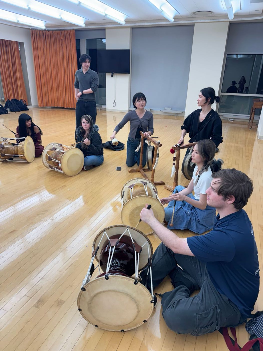 Members practicing janggu and jing in a wood-floored studio